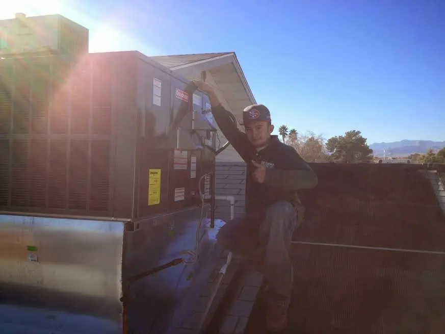 HVAC technician performing Air Duct Repair on a rooftop unit in Novi